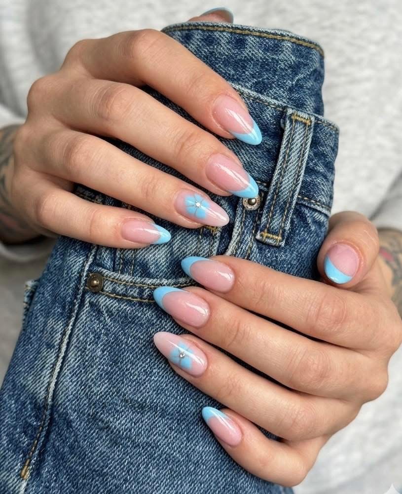Lange amandelnagels met een babyblauwe French, handen op een spijkerbroek