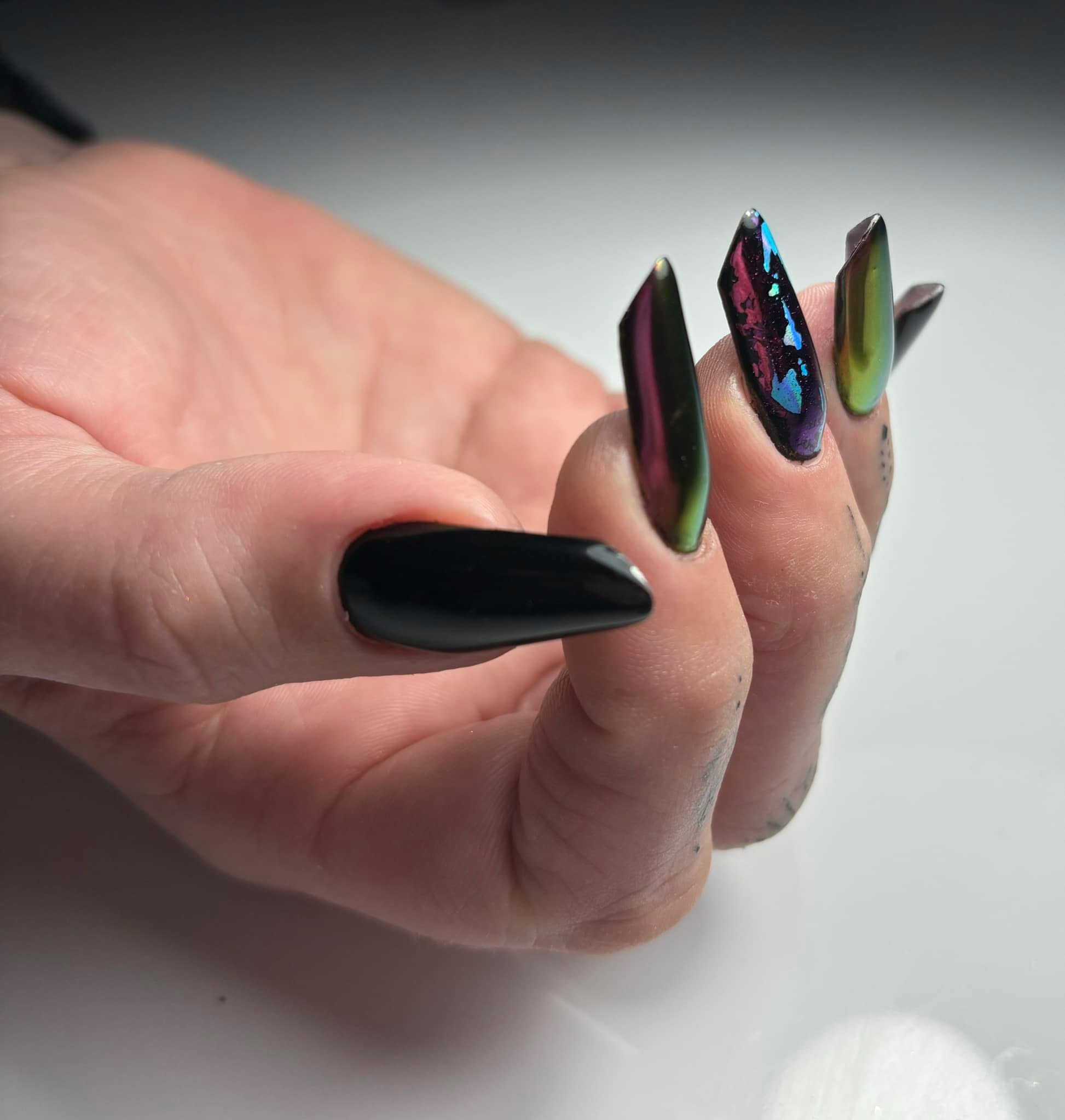 Lange nagels in zwart en kleurwisselend chroom, hand in studiolicht