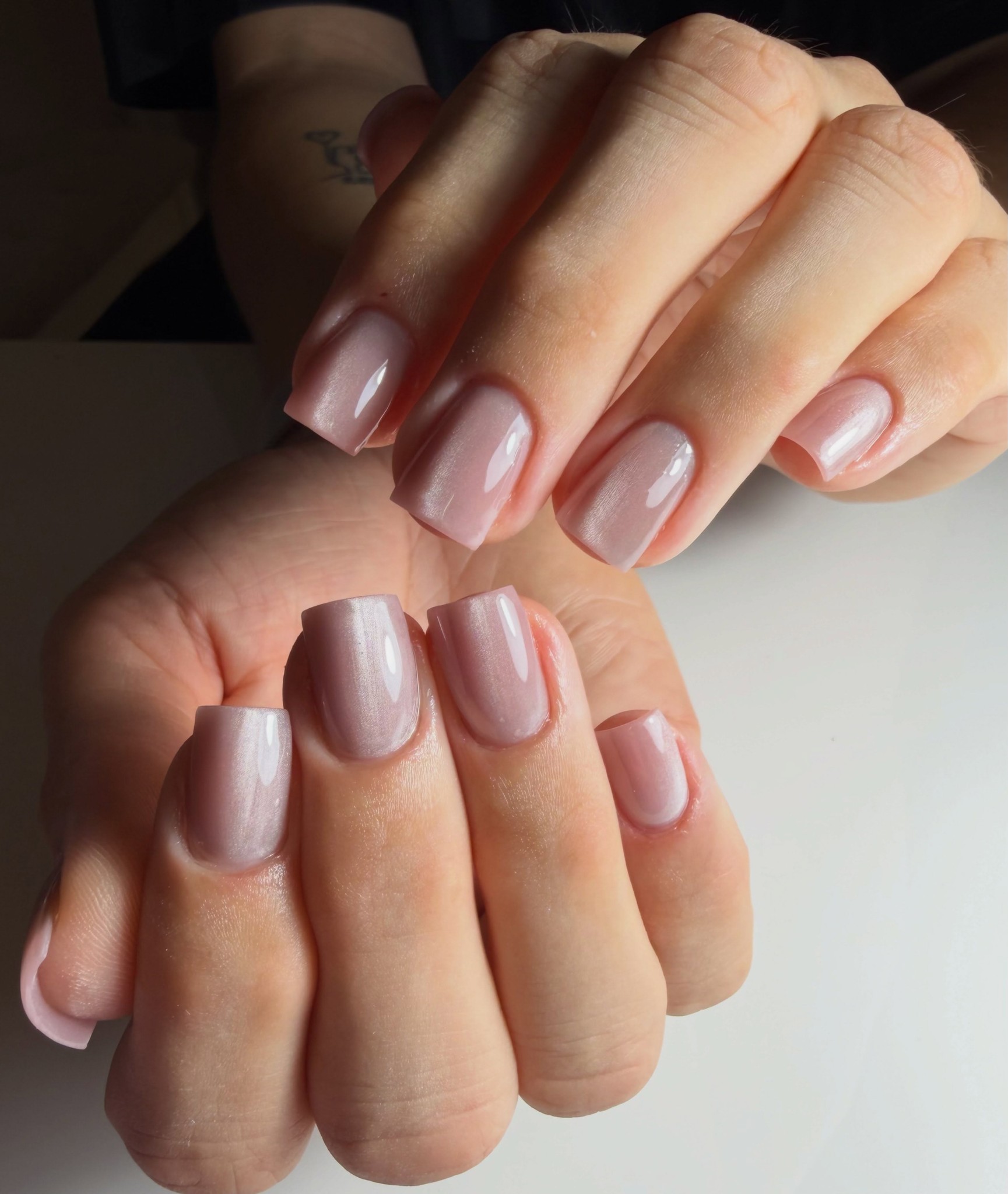 Glanzende mauve nagels in een vierkante vorm, twee handen over elkaar